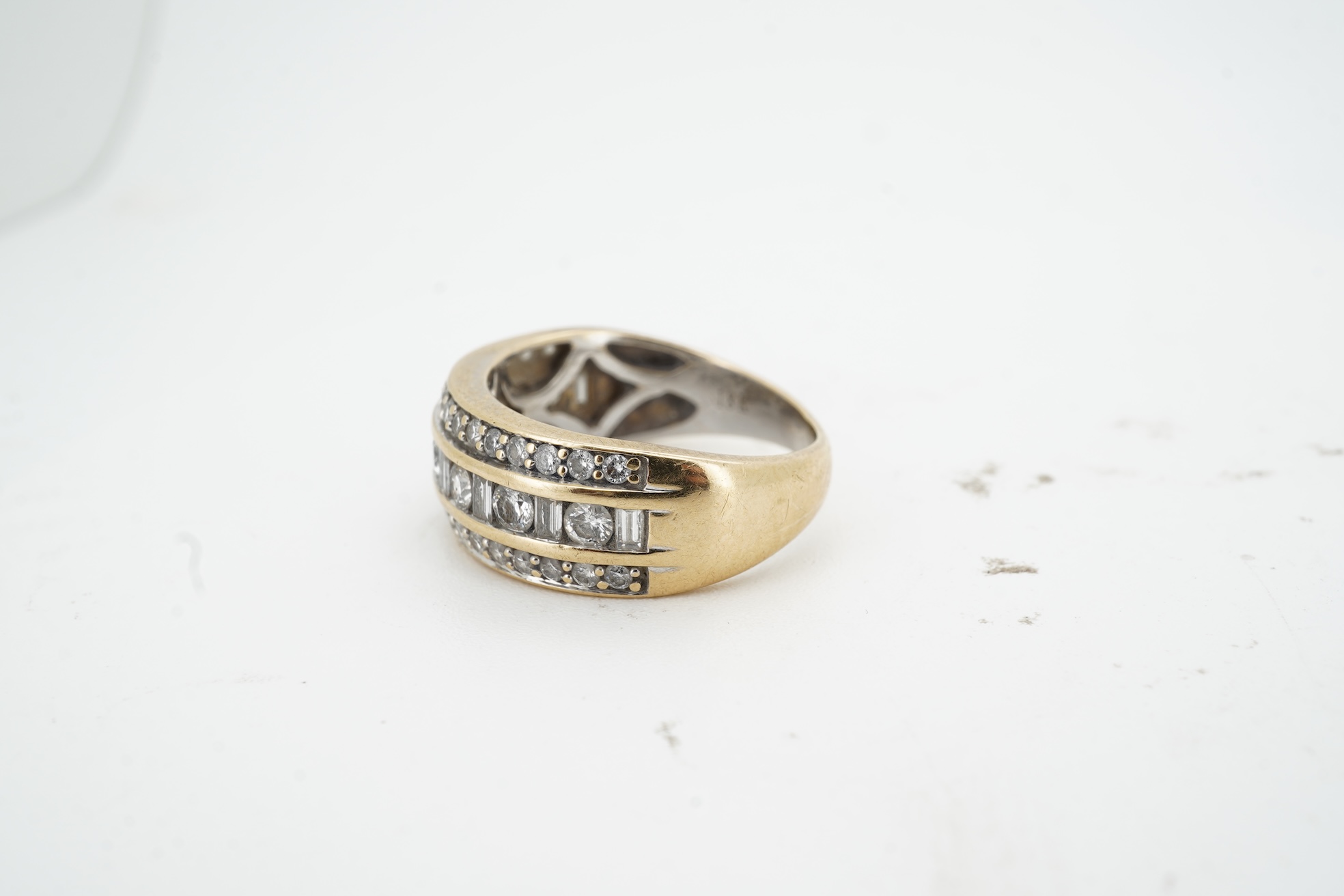 A diamond ring, the wide band set with a line of alternating brilliant-cut and baguette diamonds, between bands of brilliant-cut diamonds, mounted in gold, size M, British hallmarks for 18ct gold, total diamond weight ap